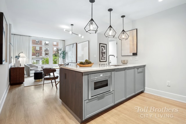 218 W 103rd St Unit 4B, New York City, NY 10025 - kitchen with gray cabinetry, a sink, light wood-style floors, light countertops, and stainless steel oven