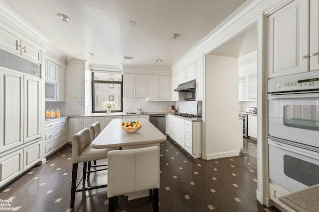 kitchen featuring a center island, appliances with stainless steel finishes, a kitchen breakfast bar, ornamental molding, and white cabinets