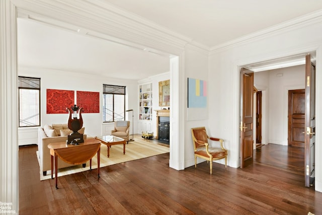 sitting room with crown molding, built in features, and hardwood / wood-style floors