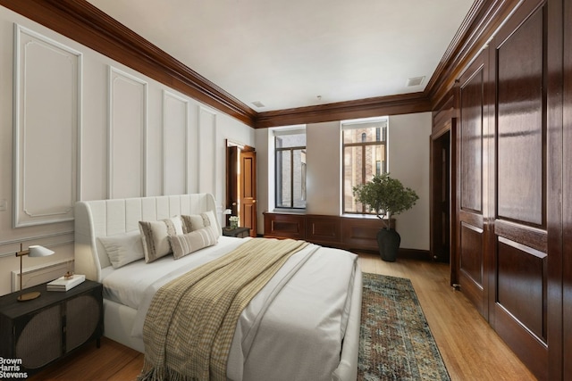 bedroom featuring crown molding and light hardwood / wood-style flooring