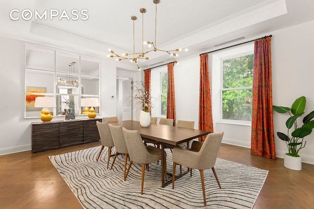 dining area with crown molding, dark parquet flooring, a tray ceiling, and an inviting chandelier