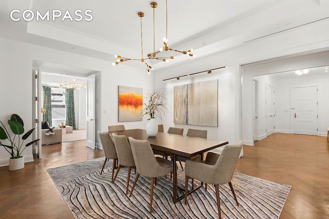 dining space featuring a raised ceiling, crown molding, and a chandelier