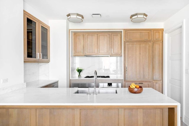 kitchen with sink, light stone countertops, and kitchen peninsula