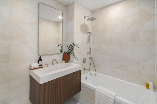 bathroom with tiled shower / bath, tile walls, and vanity