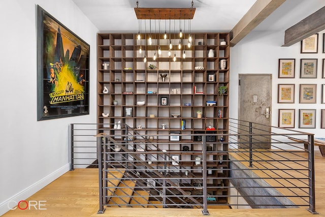 wine area featuring beamed ceiling, wood finished floors, and baseboards