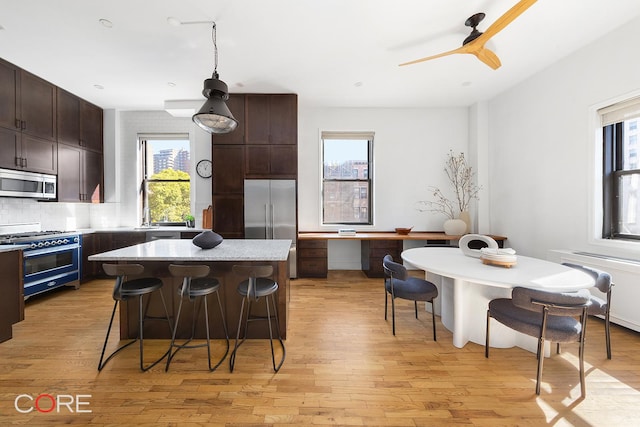 400 W 23rd St Unit 3Lk, New York City, NY 10011 - kitchen featuring high quality appliances, a kitchen breakfast bar, light wood finished floors, dark brown cabinetry, and a kitchen island
