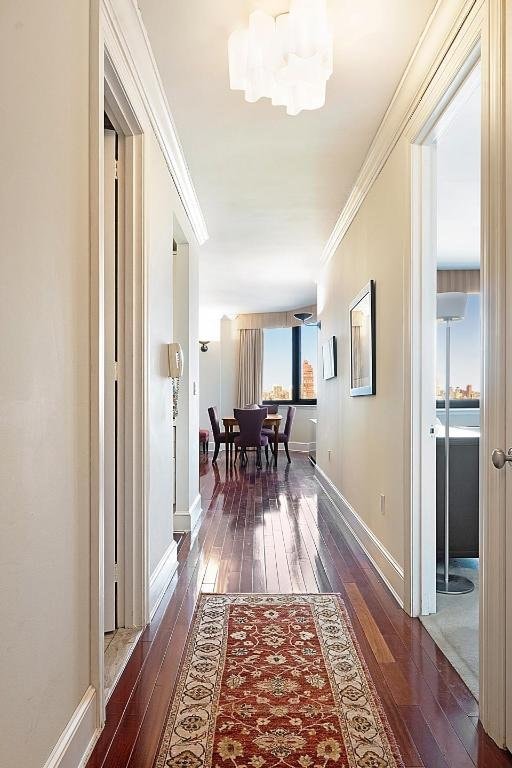 hall with a notable chandelier, ornamental molding, and dark hardwood / wood-style floors