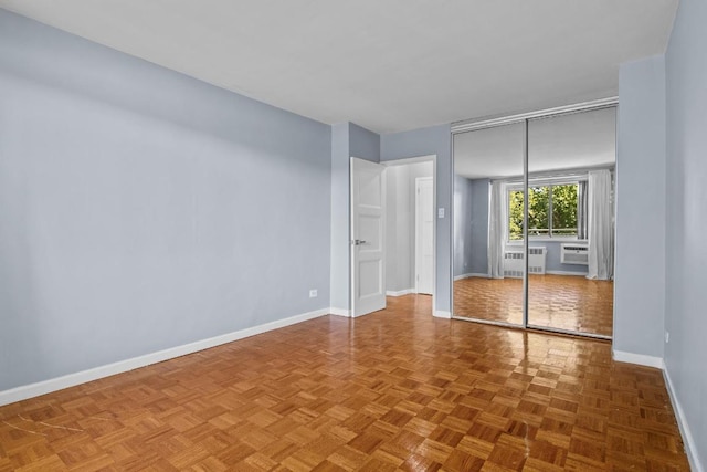 unfurnished bedroom featuring parquet floors, a wall mounted air conditioner, and a closet