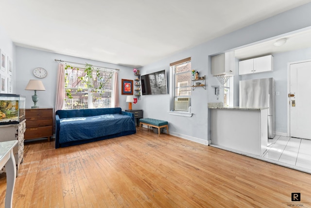 bedroom with light wood-type flooring, freestanding refrigerator, cooling unit, and baseboards