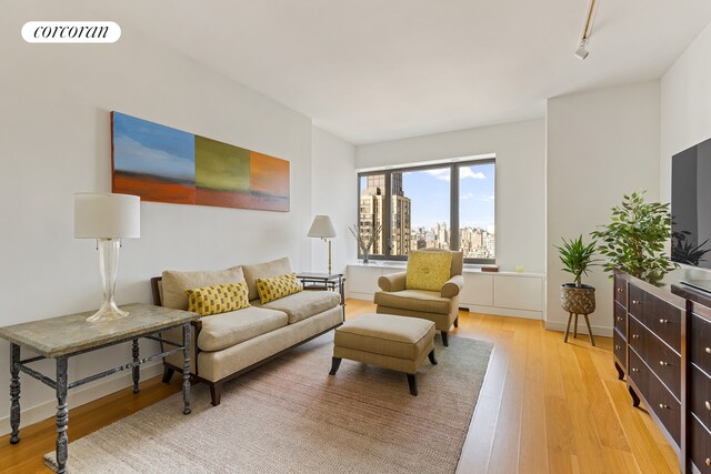 living area with rail lighting, light wood-style flooring, visible vents, and baseboards