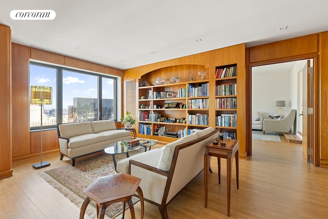 living area featuring visible vents, a view of city, light wood-type flooring, wood walls, and built in shelves