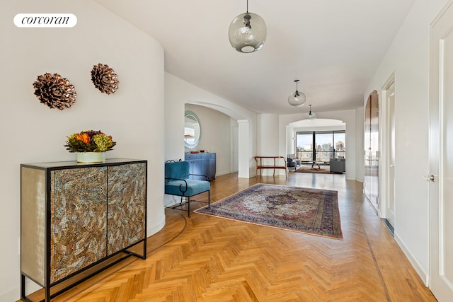 hallway featuring arched walkways, visible vents, and baseboards