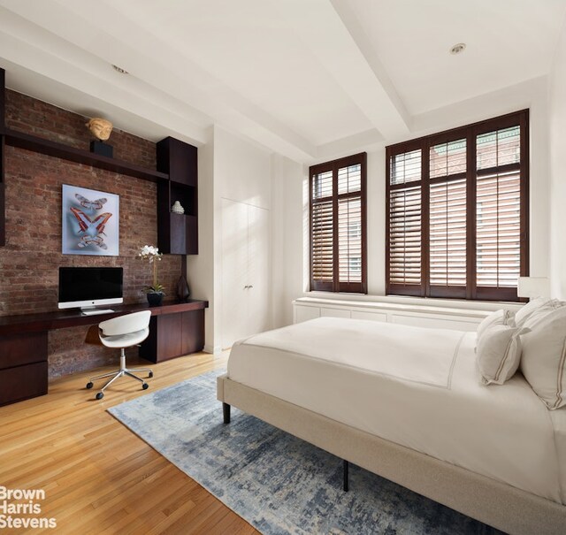 bedroom with beamed ceiling, built in desk, and wood-type flooring