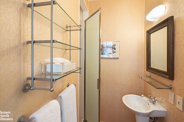 full bath with a textured wall, a sink, and a shower stall