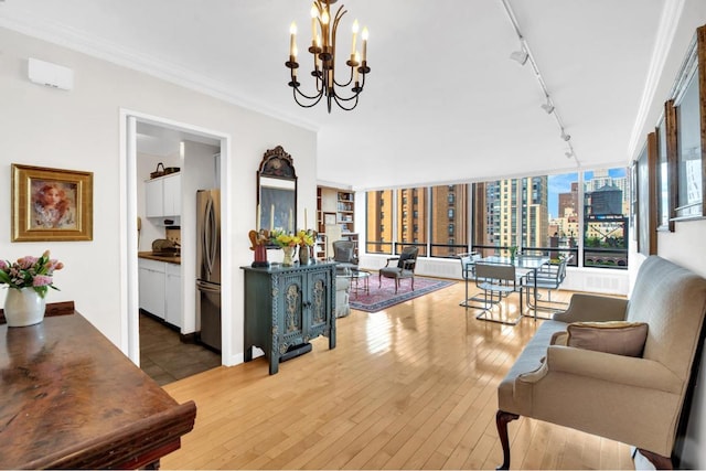 living room featuring hardwood / wood-style flooring, crown molding, track lighting, and a notable chandelier