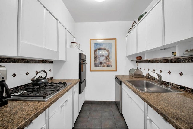 kitchen featuring decorative backsplash, sink, white cabinetry, stainless steel appliances, and dark stone counters