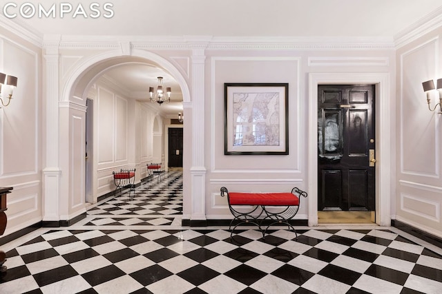 hallway featuring decorative columns, ornamental molding, and a notable chandelier