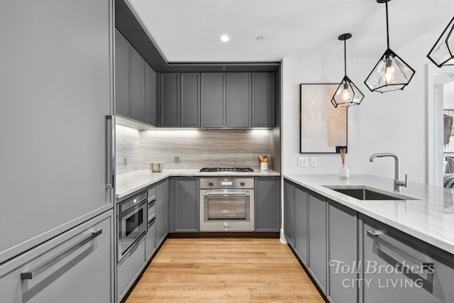 kitchen with oven, decorative backsplash, sink, hanging light fixtures, and gray cabinetry