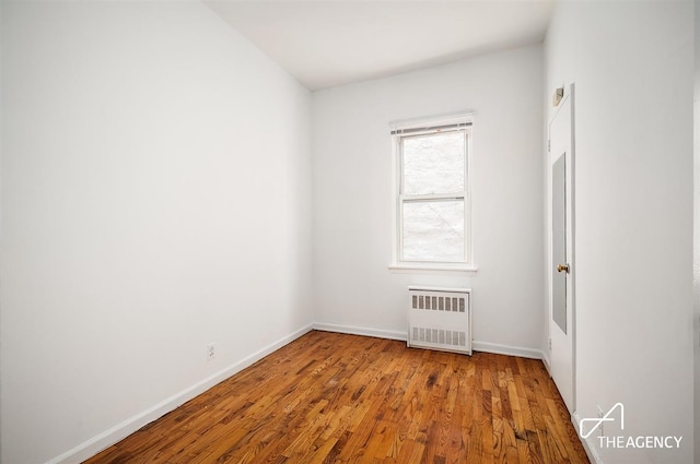 unfurnished room with baseboards, wood finished floors, and radiator heating unit