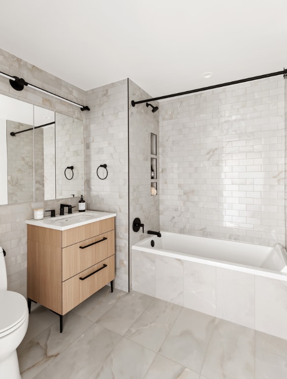 full bathroom featuring tile walls, vanity, toilet, and tiled shower / bath