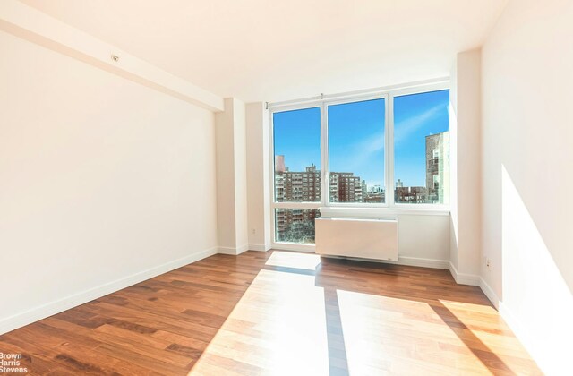 unfurnished room with floor to ceiling windows and hardwood / wood-style floors