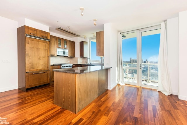 kitchen with tasteful backsplash, stainless steel appliances, kitchen peninsula, and dark wood-type flooring