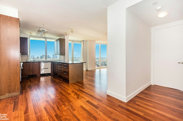 kitchen with a healthy amount of sunlight, sink, dark hardwood / wood-style flooring, and kitchen peninsula