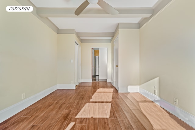 empty room with beam ceiling, ceiling fan, and light hardwood / wood-style flooring