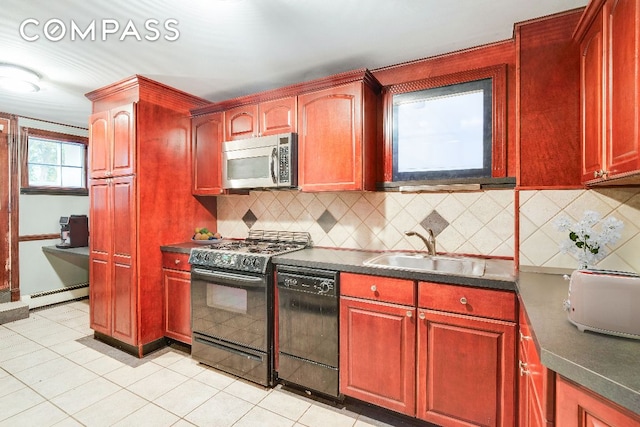 kitchen with reddish brown cabinets, dark countertops, a sink, and black appliances