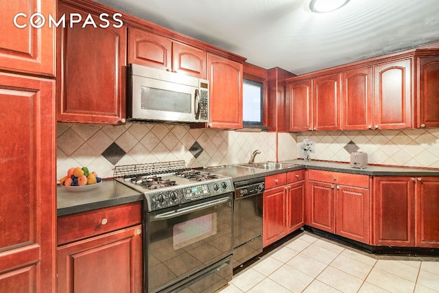 kitchen featuring black dishwasher, dark countertops, stainless steel microwave, a sink, and gas stove