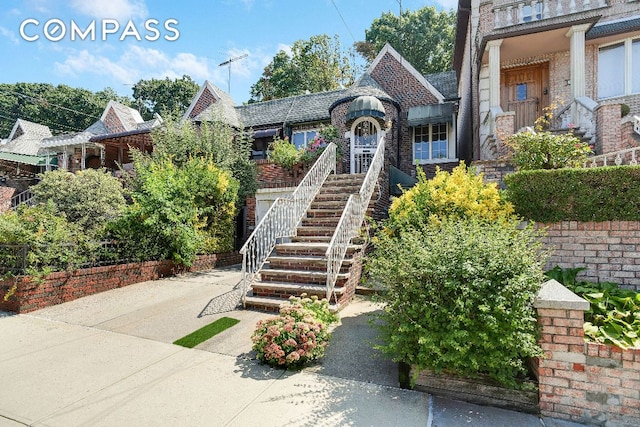 english style home featuring stairway and brick siding