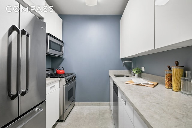kitchen featuring appliances with stainless steel finishes, a sink, white cabinetry, and light countertops