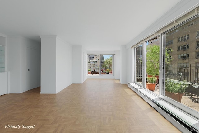 spare room featuring baseboard heating, light parquet floors, and crown molding