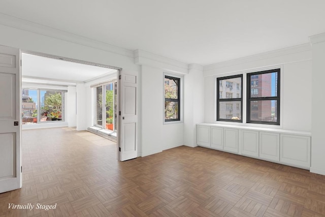 empty room with crown molding, a healthy amount of sunlight, and light parquet flooring