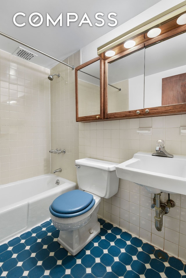 bathroom with toilet, decorative backsplash, bathing tub / shower combination, tile walls, and a sink