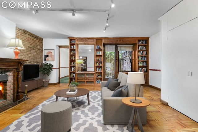 living room featuring track lighting, a fireplace, and light parquet flooring