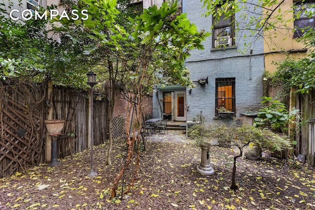 rear view of property featuring brick siding and fence