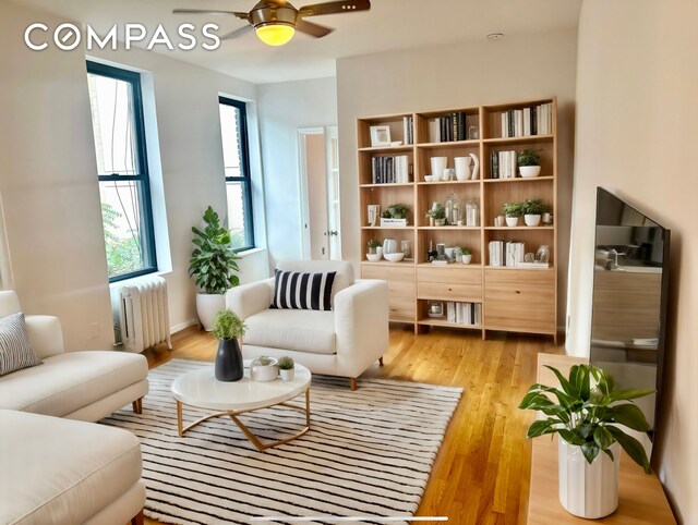 living area featuring ceiling fan, radiator, and light hardwood / wood-style floors