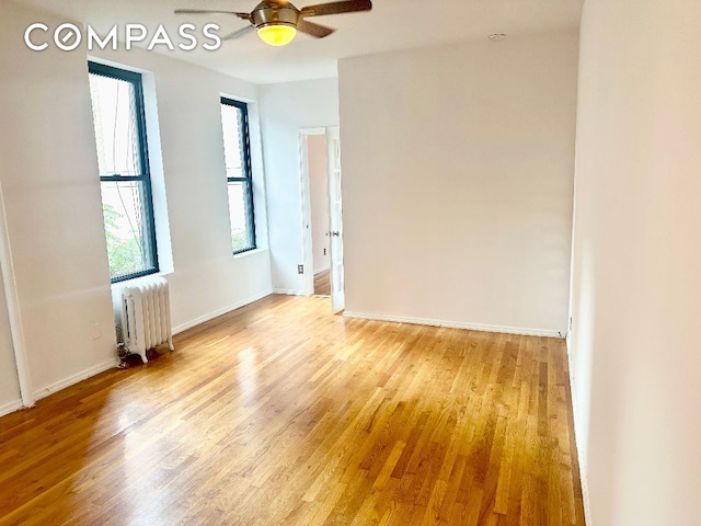 unfurnished room featuring ceiling fan, radiator heating unit, and light hardwood / wood-style flooring