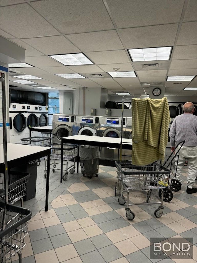 misc room with tile patterned floors, independent washer and dryer, and a paneled ceiling