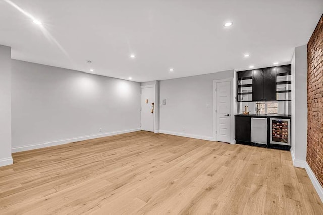 unfurnished living room featuring beverage cooler, bar, and light hardwood / wood-style floors