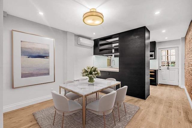 dining room featuring sink, light hardwood / wood-style floors, and a wall mounted air conditioner