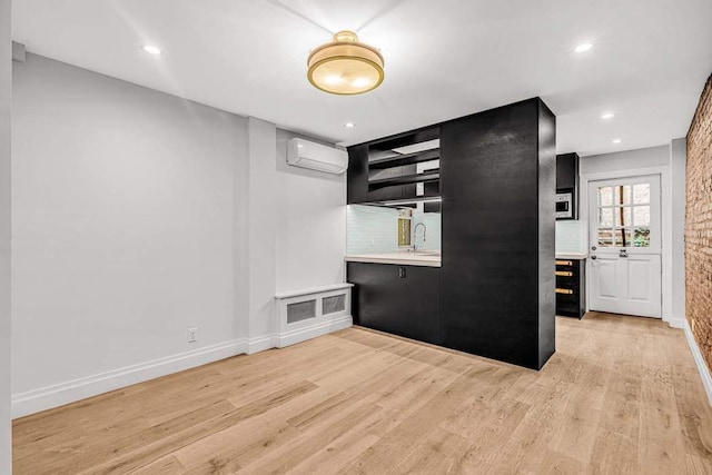 kitchen with light wood-type flooring, an AC wall unit, and sink