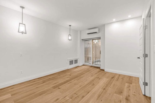 spare room featuring a wall unit AC and light hardwood / wood-style flooring