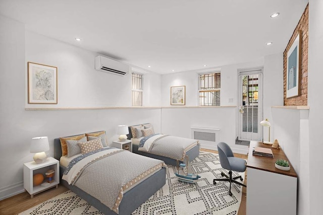 bedroom featuring an AC wall unit and light hardwood / wood-style floors