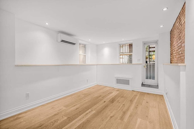 empty room featuring light wood-type flooring and a wall mounted AC