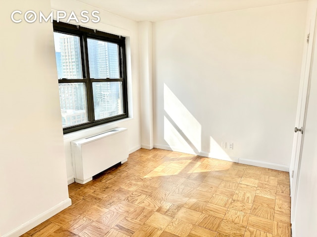 spare room with radiator heating unit and baseboards