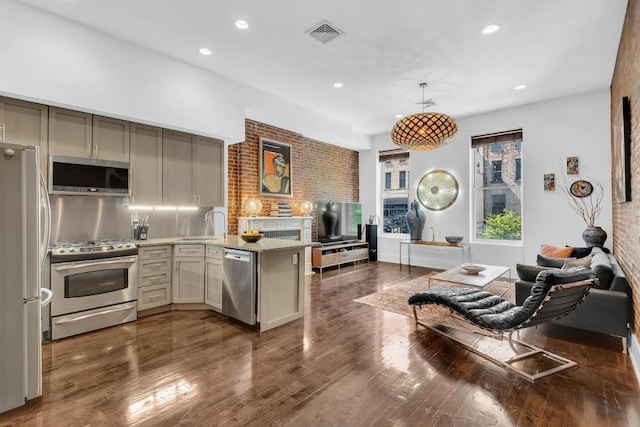 kitchen featuring kitchen peninsula, stainless steel appliances, tasteful backsplash, hanging light fixtures, and light stone countertops