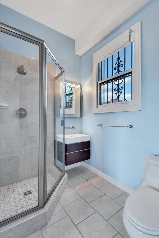 bathroom featuring a shower with shower door, vanity, tile patterned floors, and toilet