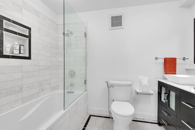 full bath with tiled shower / bath, toilet, vanity, baseboards, and visible vents